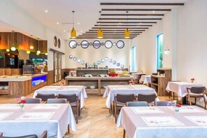 A restaurant with multiple tables, a kitchen area, and a bar. - San Chiao Hotel (Taoyuan)
