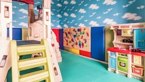 A playroom with a climbing structure, pegboard wall, and toy kitchen set. - San Chiao Hotel (Taoyuan)