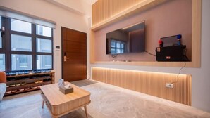 A modern hotel room with a large window, a wooden floor, a television mounted on the wall, and a shoe rack. - Tiansong Villa (Yilan)