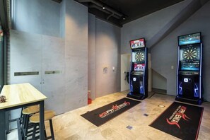 Une pièce comprenant un jeu de fléchettes, une table avec des chaises et un tapis orné d’un logo.