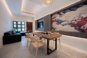 Ein modernes Wohnzimmer mit Essbereich, einem großen Gemälde an der Wand und einer Couch.