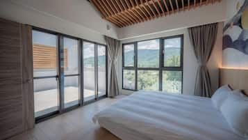 Un dormitorio con una cama grande, puertas corredizas de vidrio a un balcón y vistas al exterior.