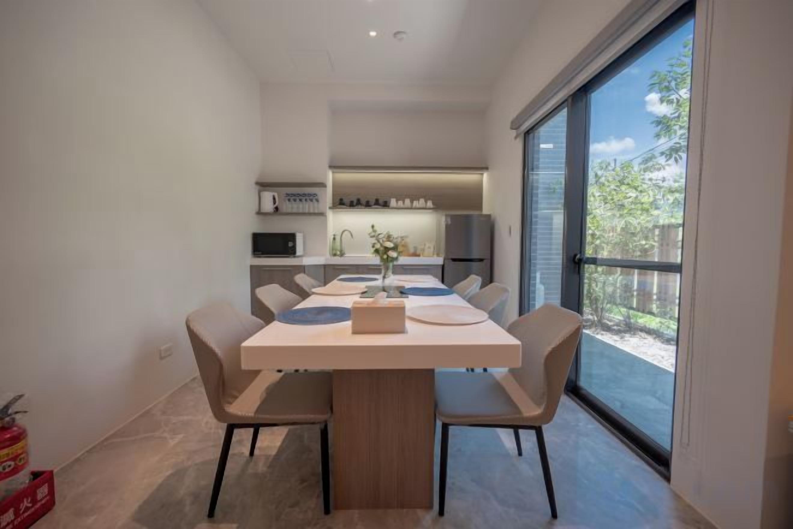 Uma sala de jantar moderna com uma mesa grande, cadeiras e vista para a cozinha.
