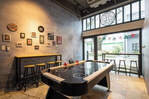A pool table in a room with a bar area, stools, and a window with a view. - Tiansong Villa (Yilan)