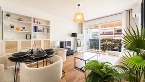 A modern living room with a dining area, white furniture, a large window, and a balcony with plants. - Apartment in Palm Beach Near Moure Rouge (Cannes)