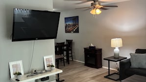 Un salon équipé d’un téléviseur à écran plat, d’un ventilateur de plafond, d’un coin repas et d’une cheminée.