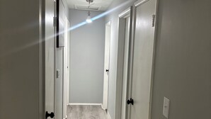Un couloir aux murs gris et au plancher en bois, qui mène à plusieurs portes.