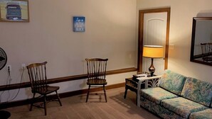 A room with two wooden chairs, a patterned sofa, a lamp, and a mirror on the wall. - Beach Side HideAway - Pet Friendly, WiFi, Smart TV, Central Heat/AC, Parking (Norfolk)