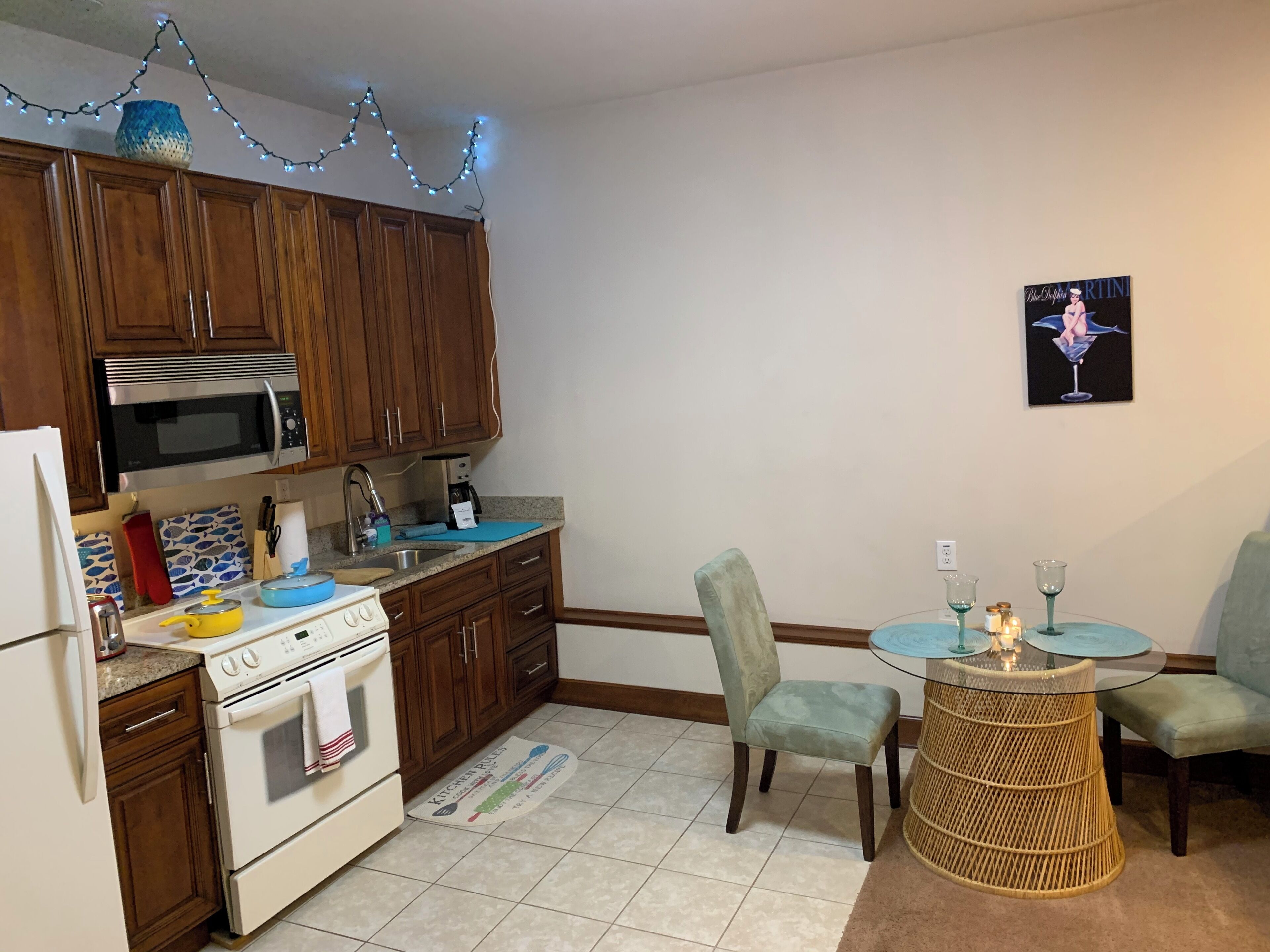Una cocina con armarios de madera, microondas, estufa y un comedor con sillas y una mesa.