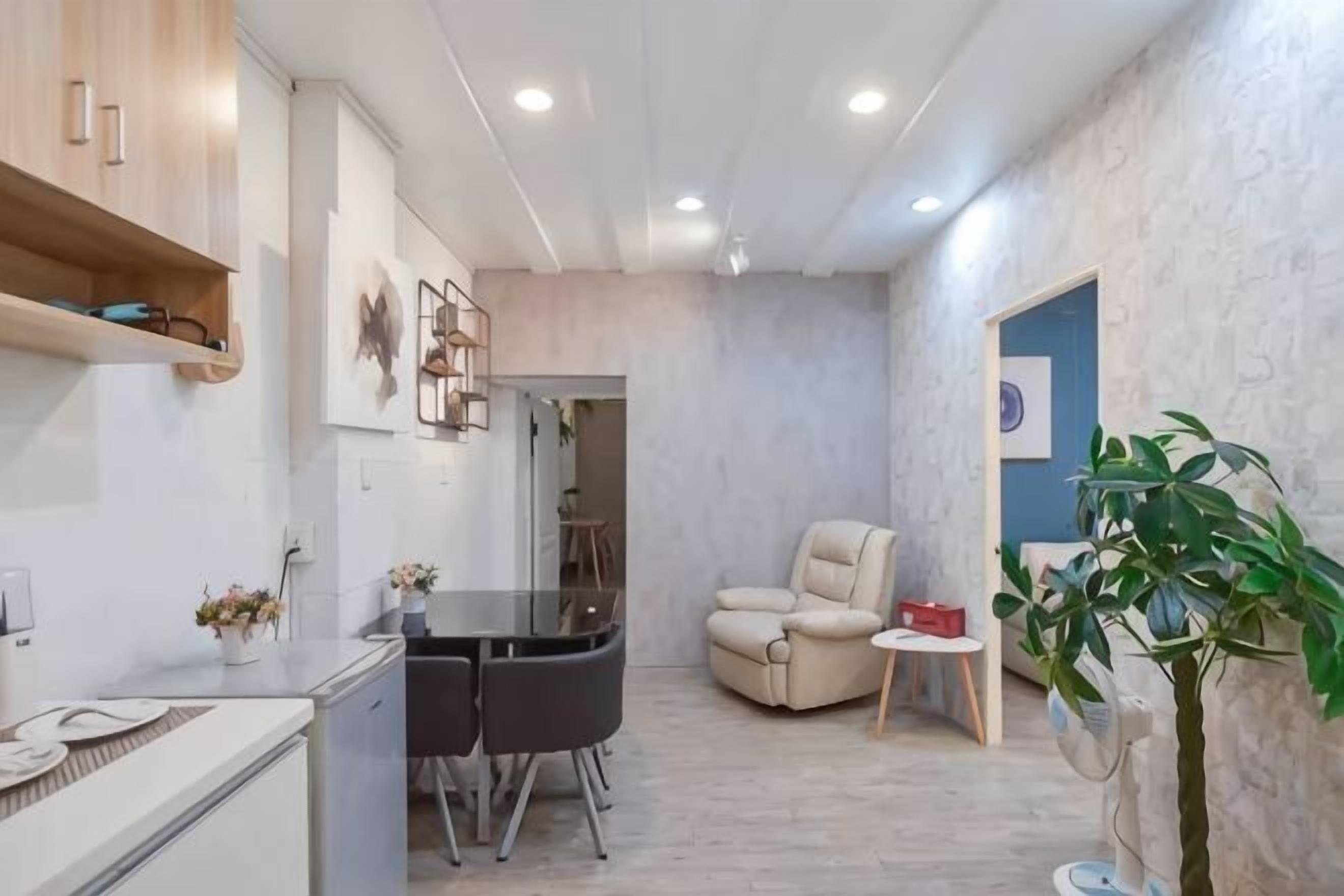 A compact living space with a kitchenette, a dining area, a seating area, and a small plant.