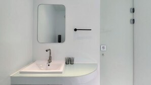 Un baño moderno con un lavamanos blanco, un espejo y una puerta.
