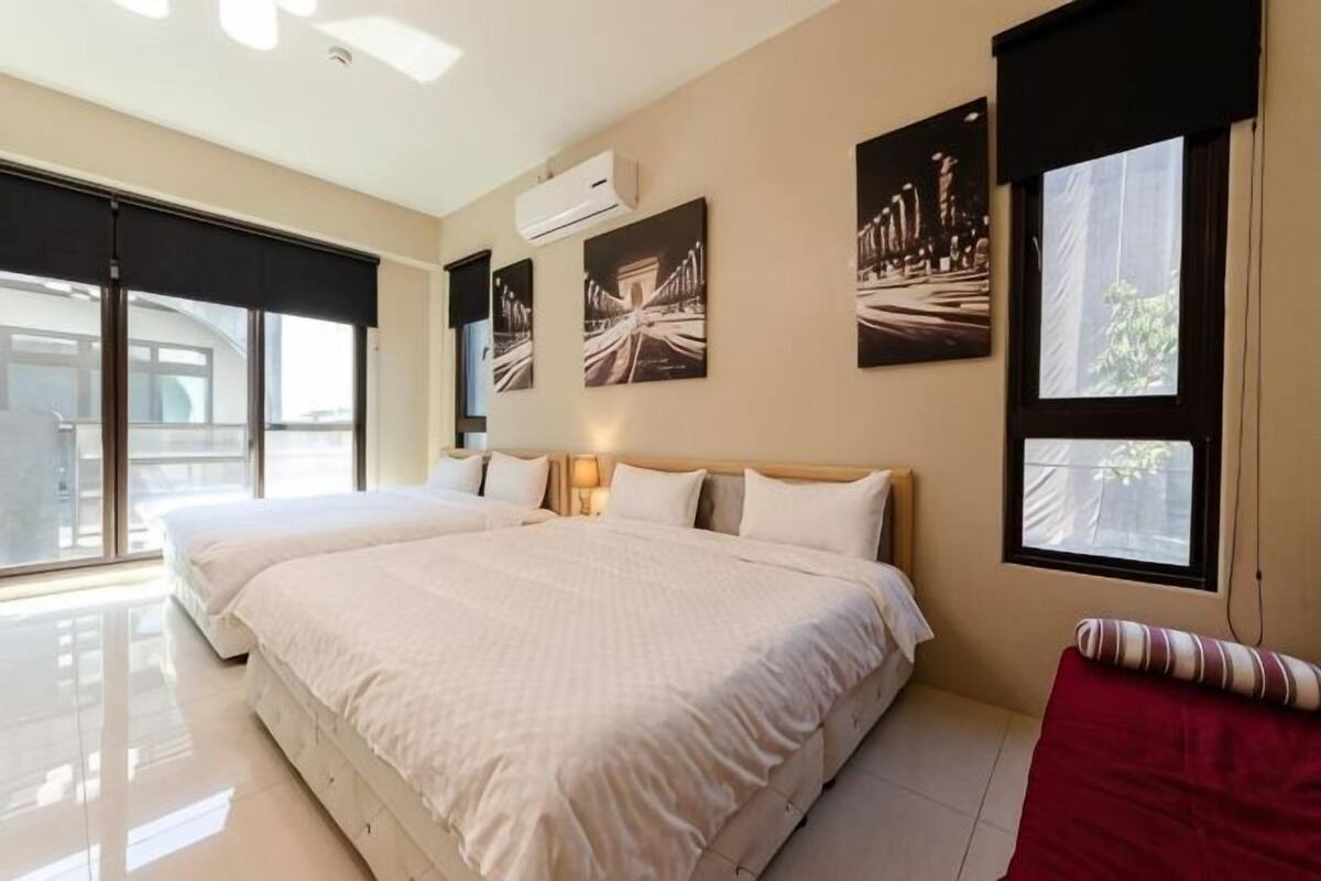 Een hotelkamer met een groot bed, een rode stoel en kunstwerken aan de wanden.