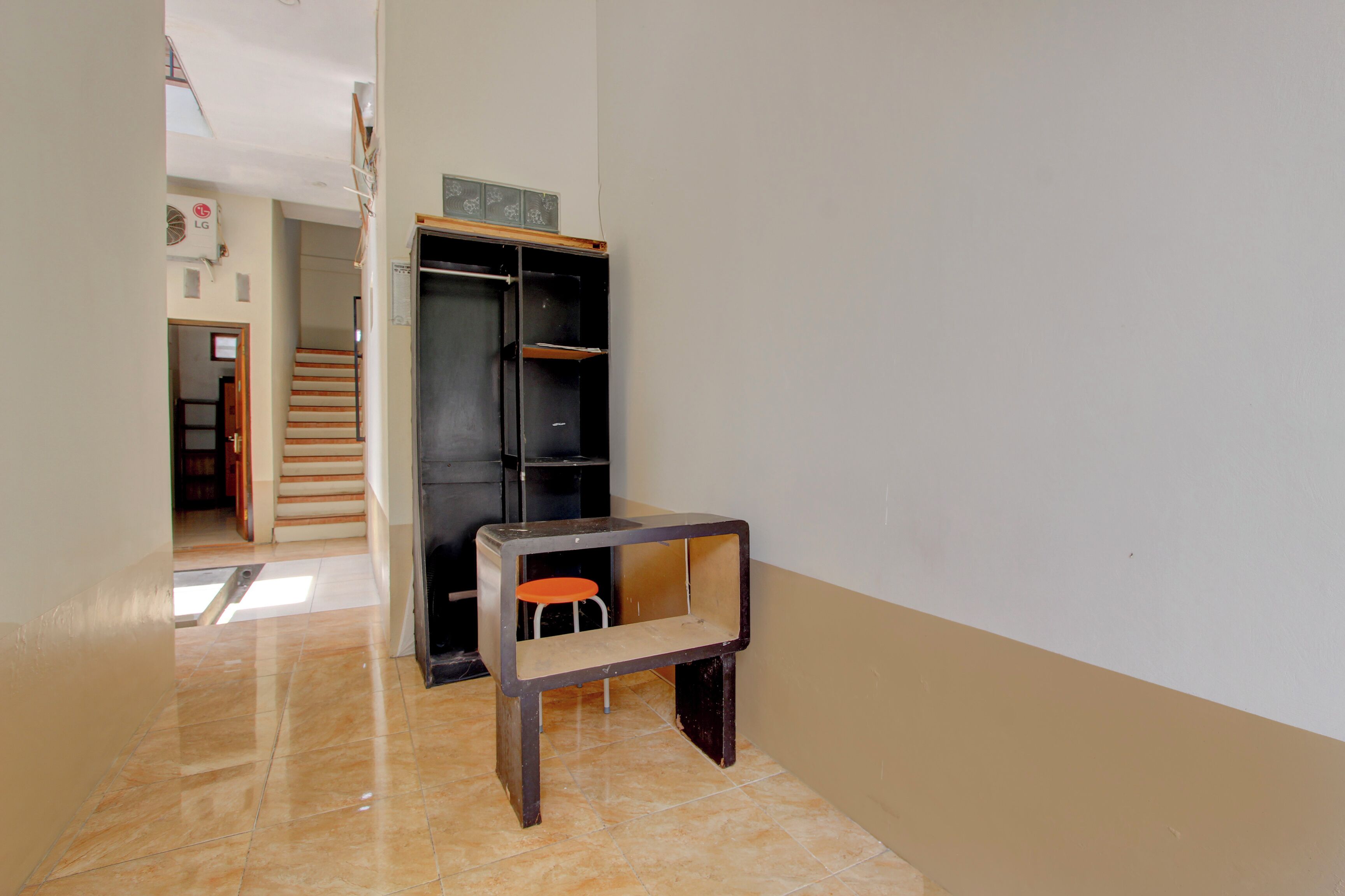 A hallway with a tiled floor, a wooden bench, and a black wardrobe with a small stool.