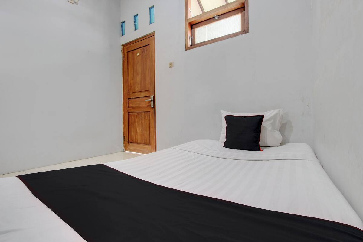 Un dormitorio con cama, una puerta de madera y una ventana.