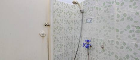 A shower area with a handheld showerhead and a wall-mounted faucet.