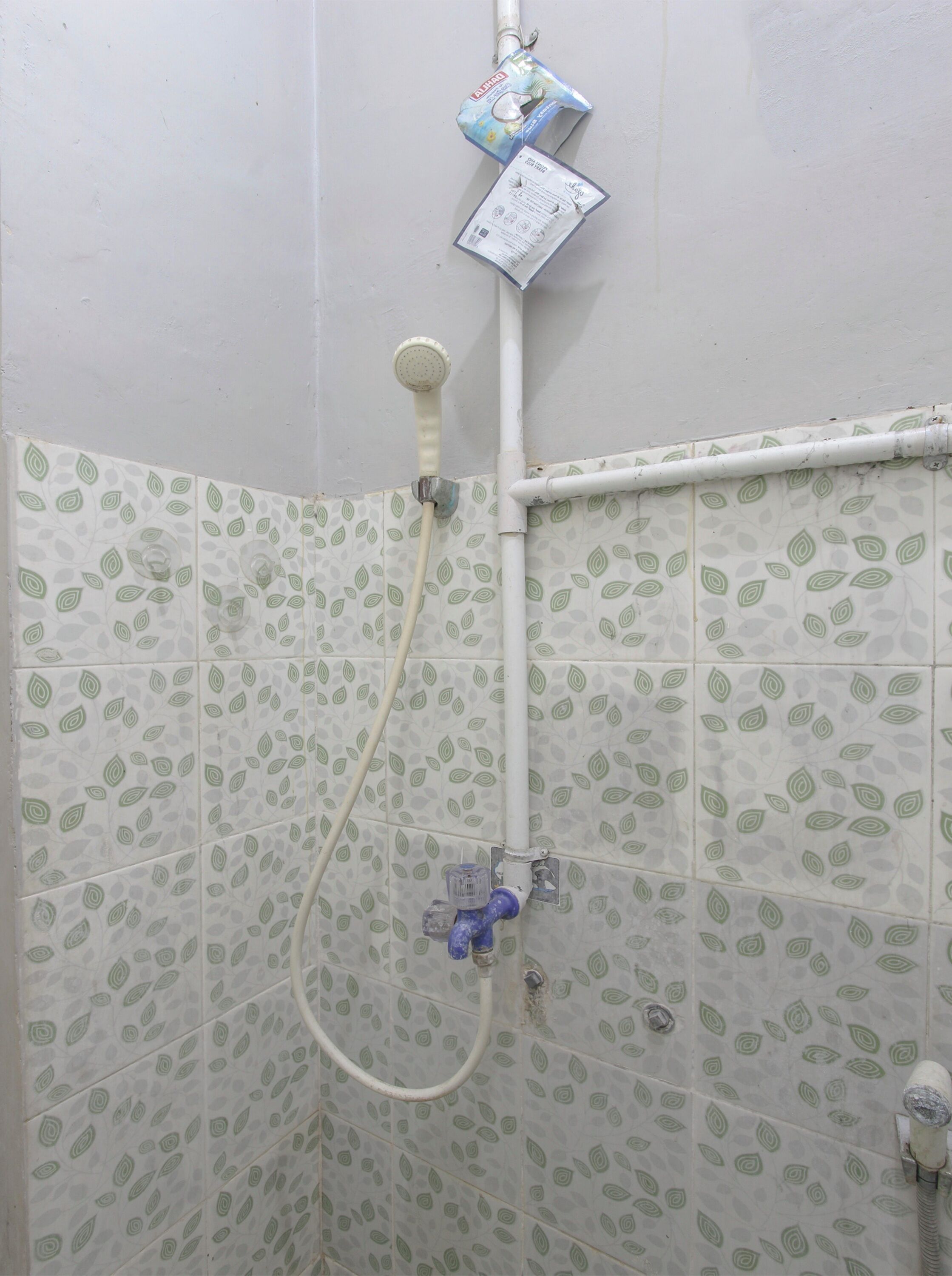 A shower with a handheld showerhead and a wall-mounted faucet.