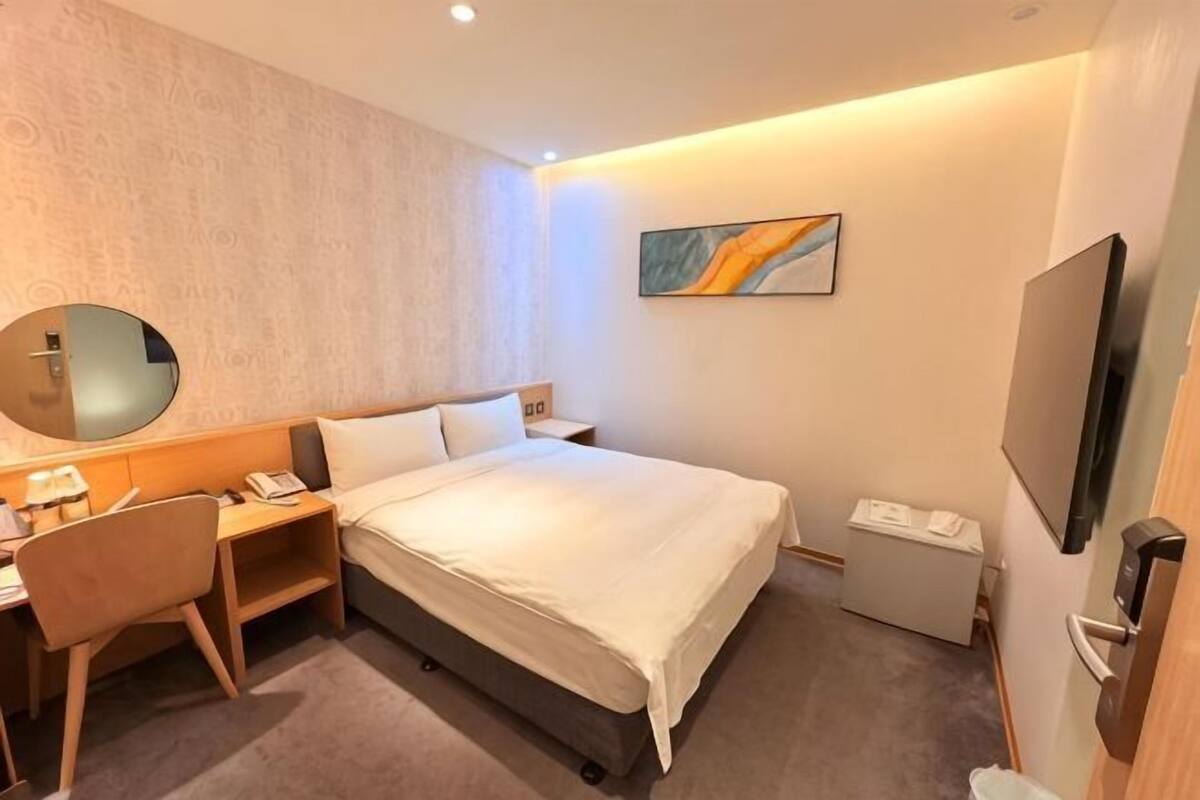 Une chambre d’hôtel avec un lit, un bureau, une chaise, une télévision et un tableau au mur.