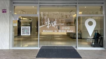 A hotel entrance with a glass door, a welcome sign, and a location pin icon.