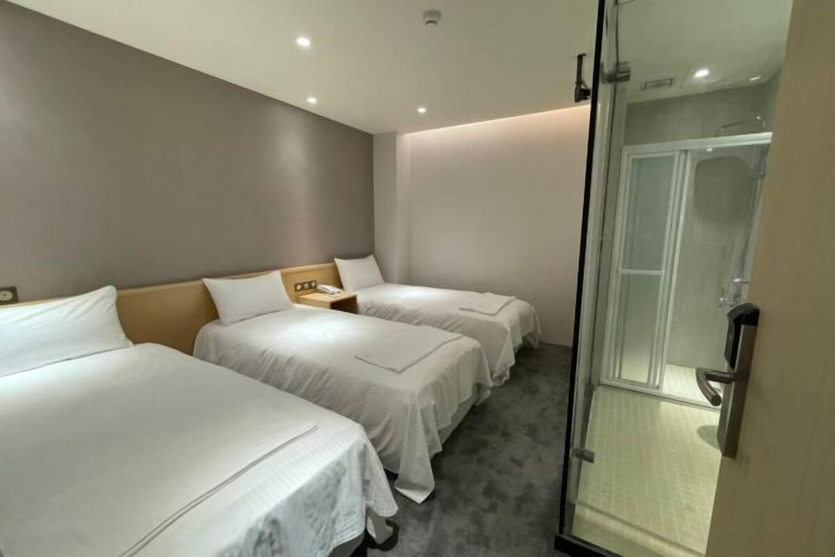 Une chambre d’hôtel avec deux lits, une douche et une porte en verre.