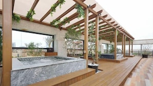 A rooftop terrace with a hot tub, wooden decking, and a pergola with climbing plants. - Gamalan Star Hotel (Yilan)