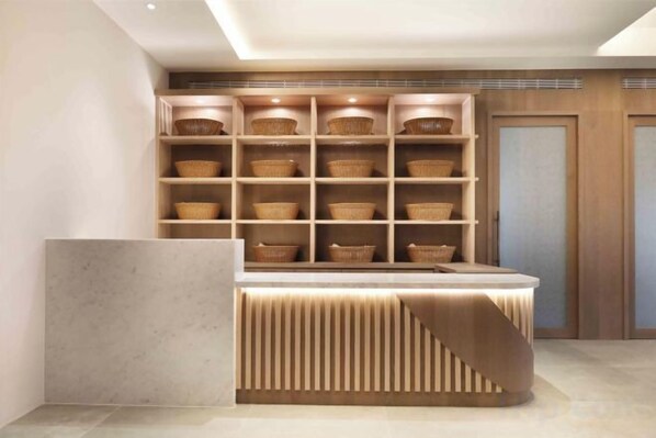 A modern interior with a built-in shelving unit filled with baskets, a central counter, and a wooden door in the background. - Gamalan Star Hotel (Yilan)