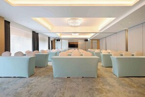 A conference room with rows of chairs, a chandelier, and a large screen. - Gamalan Star Hotel (Yilan)