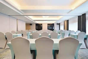 A conference room with rows of tables and chairs, a large screen, and a view of the outdoors. - Gamalan Star Hotel (Yilan)