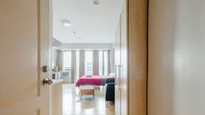 Ein Hotelzimmer mit Bett, Schreibtisch, Stuhl und einem fensterbepflanzten Fenster.