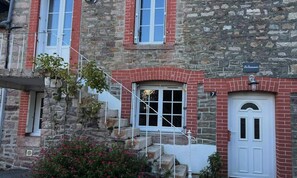 Ein Gebäude aus Stein mit einer roten Backsteinfassade, einer weißen Tür und einem kleinen Fenster mit weißem Rahmen.