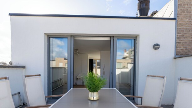A modern outdoor seating area with a long table, chairs, and a potted plant. - Florence with private garage by Interhome (Oostende)