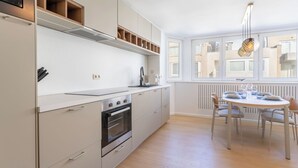 A modern kitchen with white cabinets, a built-in oven, and a dining area with a table and chairs. - Florence with private garage by Interhome (Oostende)