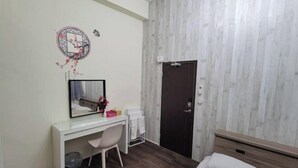 Une chambre à coucher comprenant un lit, un bureau avec une chaise, un miroir, une porte et un mur orné d’un motif.
