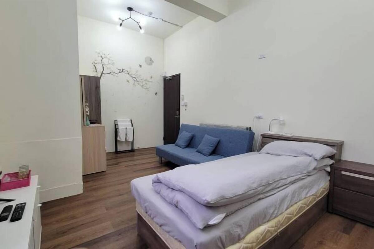 Una camera da letto con un letto, un divano blu, un armadio e una scrivania.