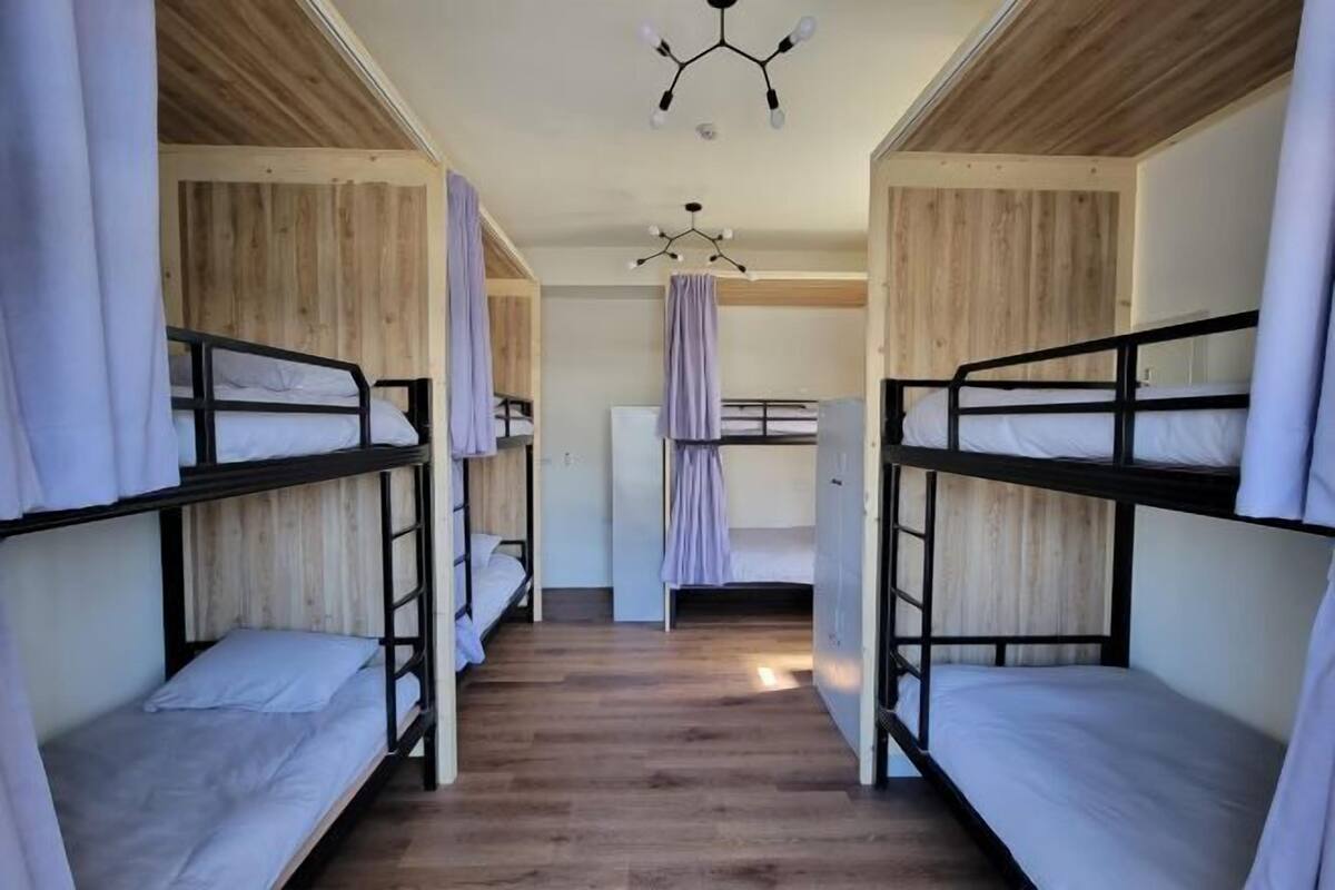 Una camera del dormitorio con letti a castello, pareti in legno e una lampada a sospensione.