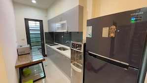 Eine kleine Küche mit einem Edelstahl-Kühlschrank, einer Mikrowelle und einem Spülbecken.