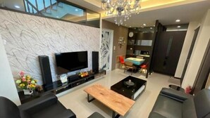 Ein modernes Wohnzimmer mit einem Flachbildfernseher, einem Holztisch und schwarzen Ledersofas.