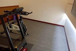 A treadmill in a room with a carpeted floor and a red border along the wall. - Hi-YES HOTEL TAOYUAN (Taoyuan)