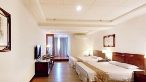 Une chambre d’hôtel avec un plancher en bois, deux lits, une télévision, un bureau et une chaise.