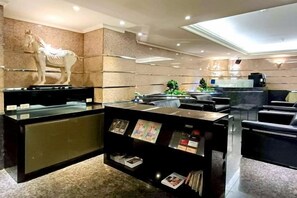 A reception area with a reception desk, a statue, and a display of brochures. - Hi-YES HOTEL TAOYUAN (Taoyuan)