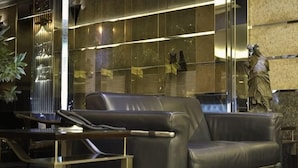 A modern lobby with a leather sofa, a glass partition, and a statue. - Hi-YES HOTEL TAOYUAN (Taoyuan)