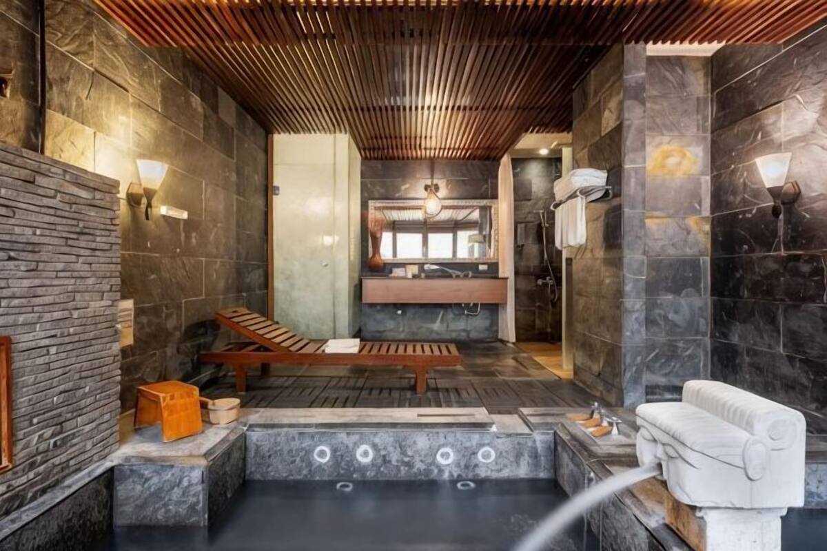 A spa area with a stone wall, wooden ceiling, and a seating area with a bench and a small table.