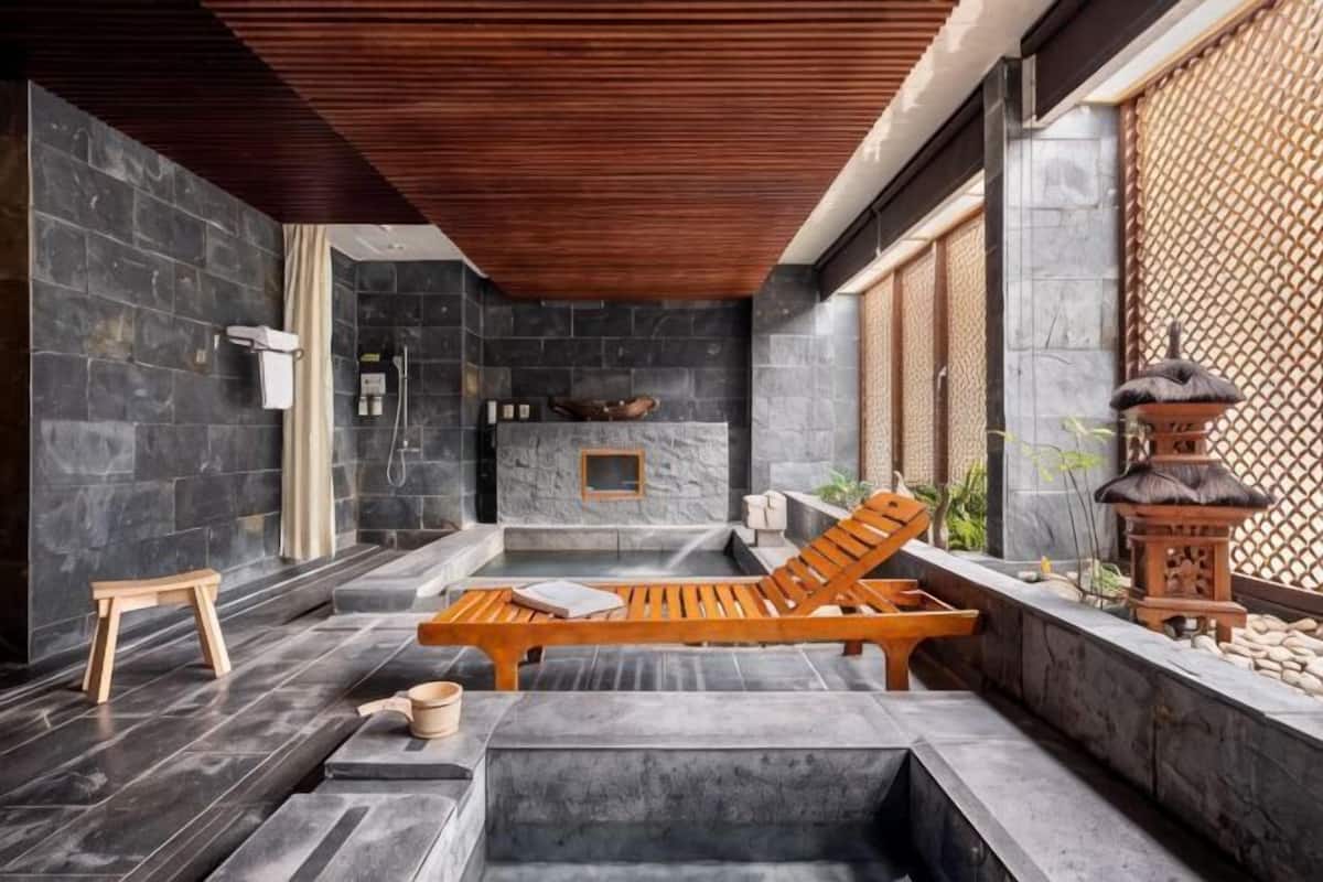 A spa area with stone walls, a wooden ceiling, a stone fireplace, and a seating area with a wooden bench and cushions.