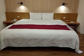 A large bed with white linens and a red throw blanket, two bedside tables with lamps, and a wooden headboard. - Bali Nature Spa Hotspring Resort (Taichung)