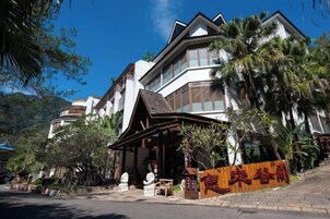 A multi-story hotel with a traditional architectural style, featuring a prominent entrance with a wooden facade and signage.