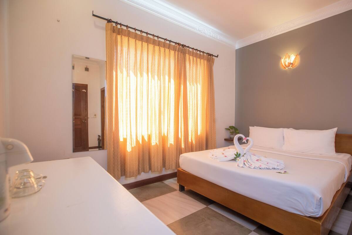 Una habitación de hotel con una cama grande, un escritorio y una ventana con cortinas.