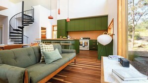 Un salon moderne avec un canapé vert, une table basse en bois et un escalier en colimaçon.