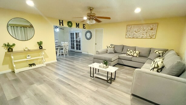 Una sala de estar con un sofá gris, una mesa de centro y una consola blanca con objetos decorativos.