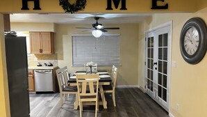Un interior de hogar con comedor, cocina y un reloj en la pared.