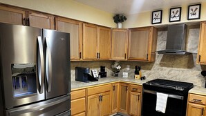 Una cocina con armarios de madera, un refrigerador de acero inoxidable, una cafetera y una estufa.