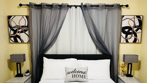 Una cama con dosel, dos mesitas de noche con lámparas y dos cuadros abstractos en las paredes.